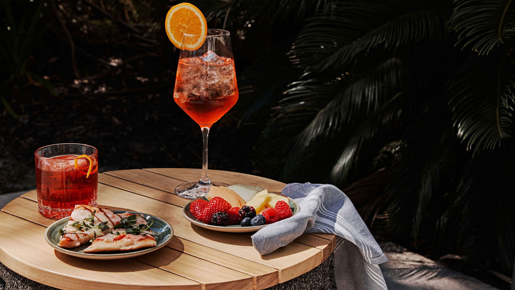 Aperol spritz and pizza in front of greenery